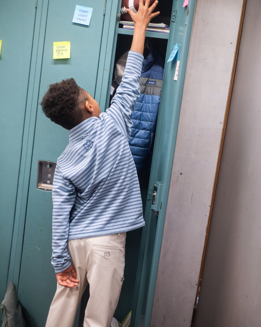Person reaching into a locker with another person inside, against a wall with a light switch.