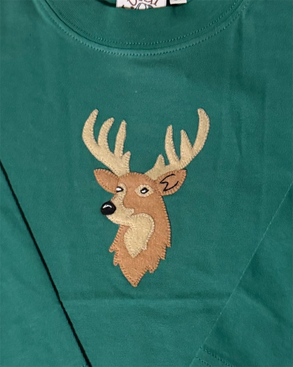 Green shirt with a deer head patch on a green background