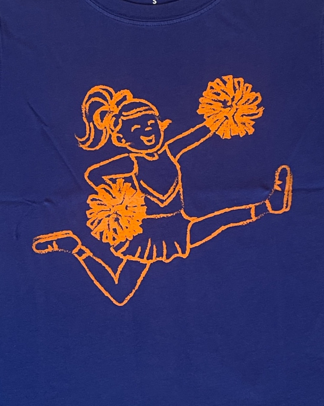 Blue t-shirt with orange embroidered design of a cheerleader on a blue background