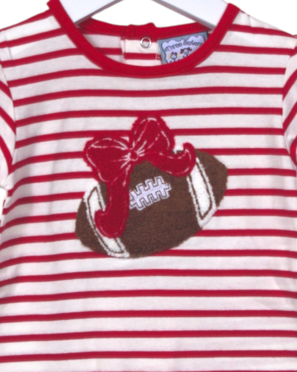 Red and white striped shirt with a football and bow design on a hanger.