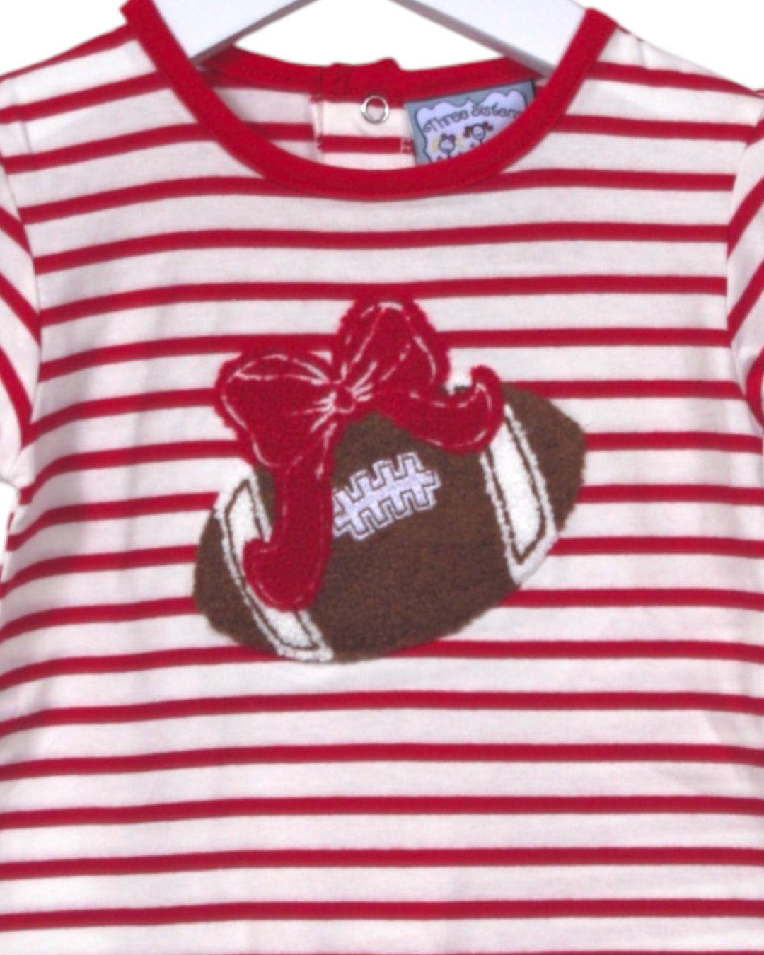Red and white striped shirt with a football and bow design on a hanger.