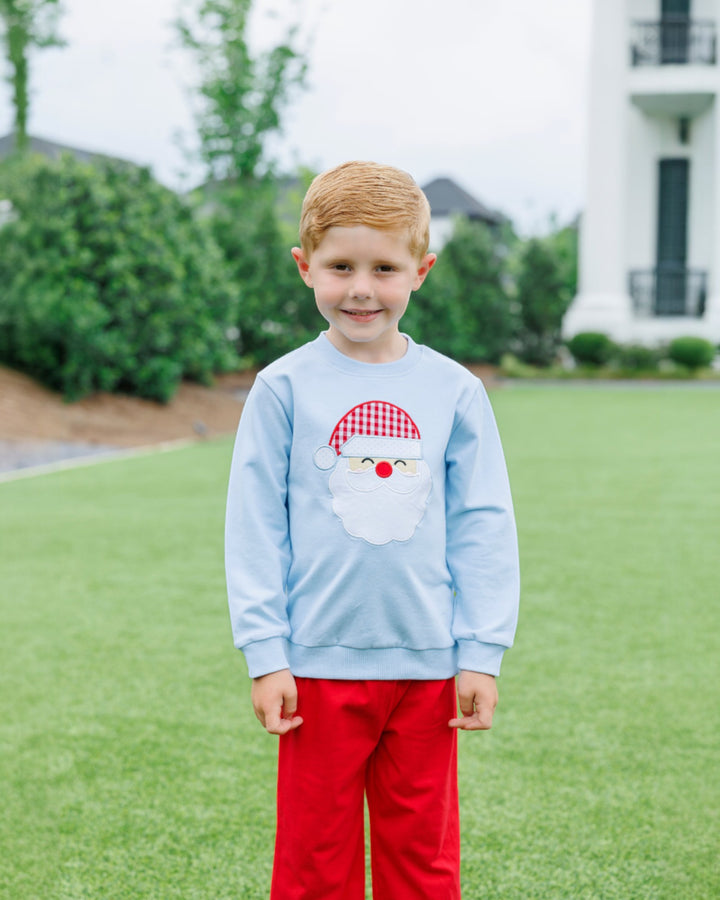 Child wearing a light blue sweatshirt with a cartoon face design outdoors.