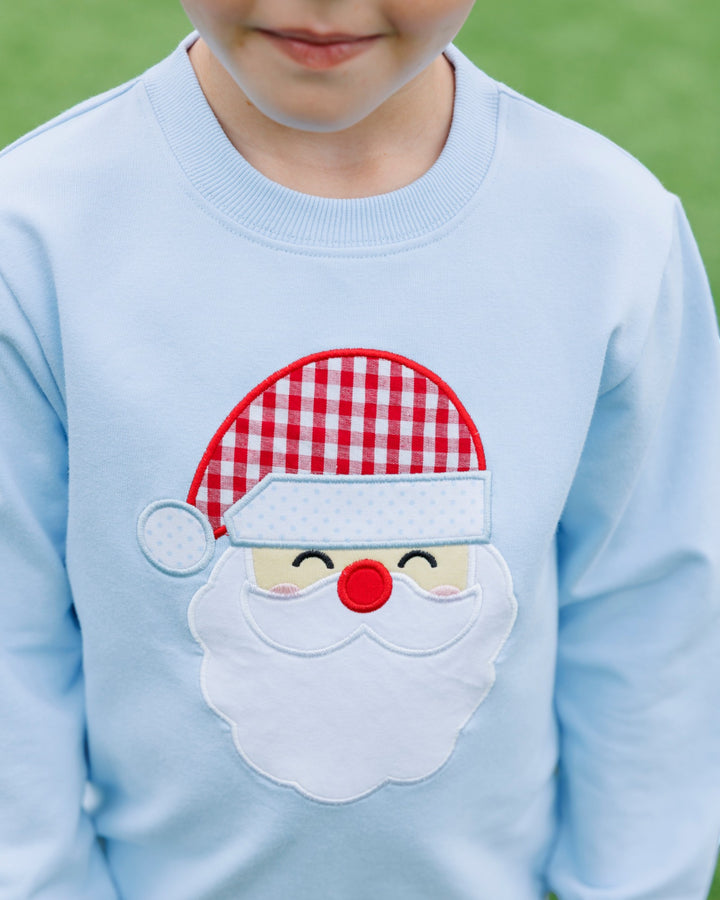 Light blue sweater with a Santa Claus patch on a grassy background