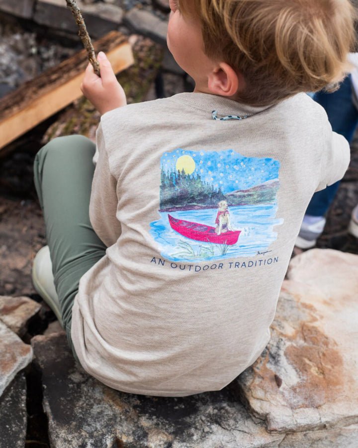 Child wearing a shirt with a graphic of a child in a red kayak on a natural background