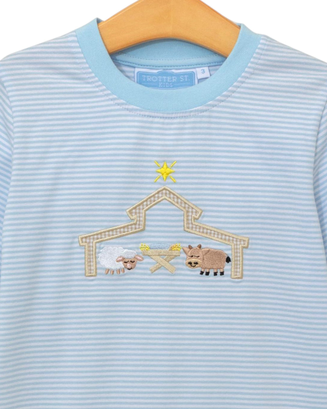 Light blue striped shirt with a embroidered nativity scene on a hanger