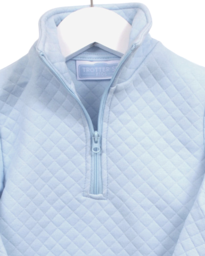 A light blue quilted quarter-zip pullover sweater hanging on a white hanger, showing the collar and zipper detail against a plain white background, that store