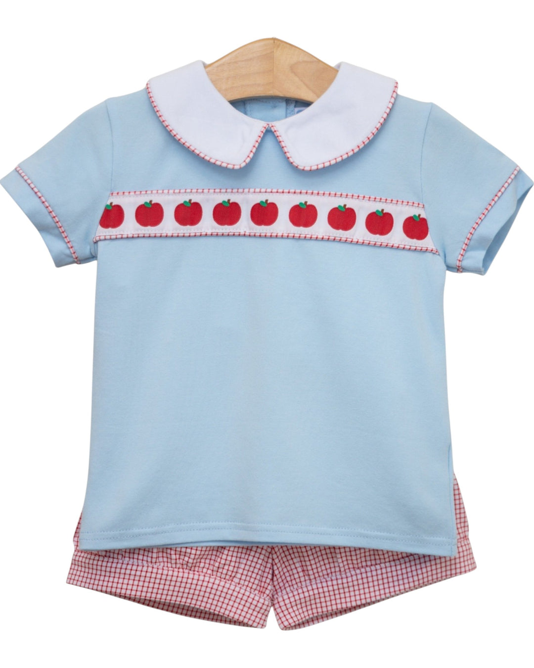 Children's outfit with light blue top and red checkered shorts on a white background