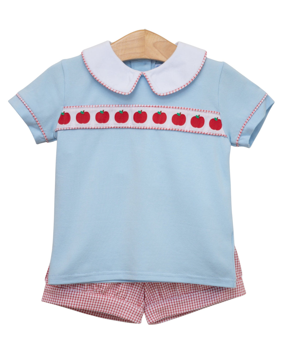 Light blue top with red apple pattern and pink checkered shorts on a hanger