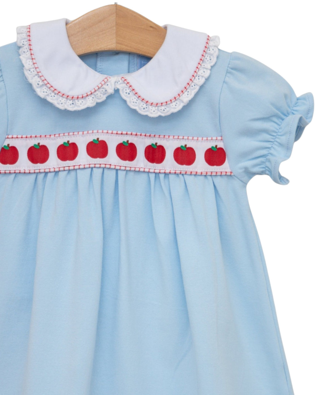 Light blue dress with white collar and red apple pattern on a wooden hanger