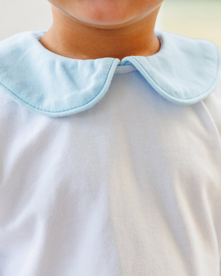 Close-up of a child wearing a white top with a light blue Peter Pan collar.