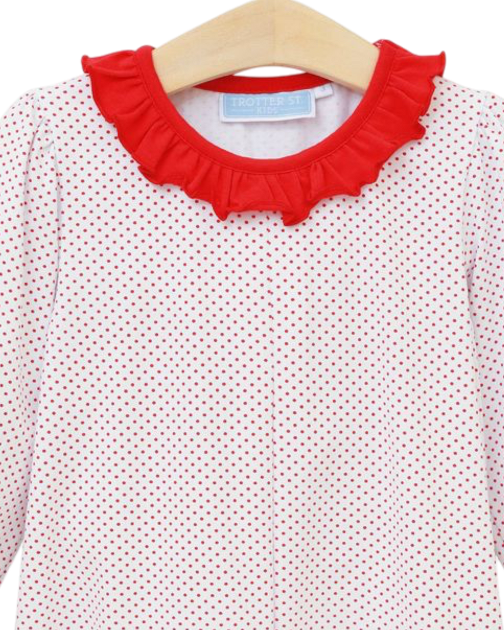 White blouse with red polka dot pattern and red ruffled collar on a hanger.