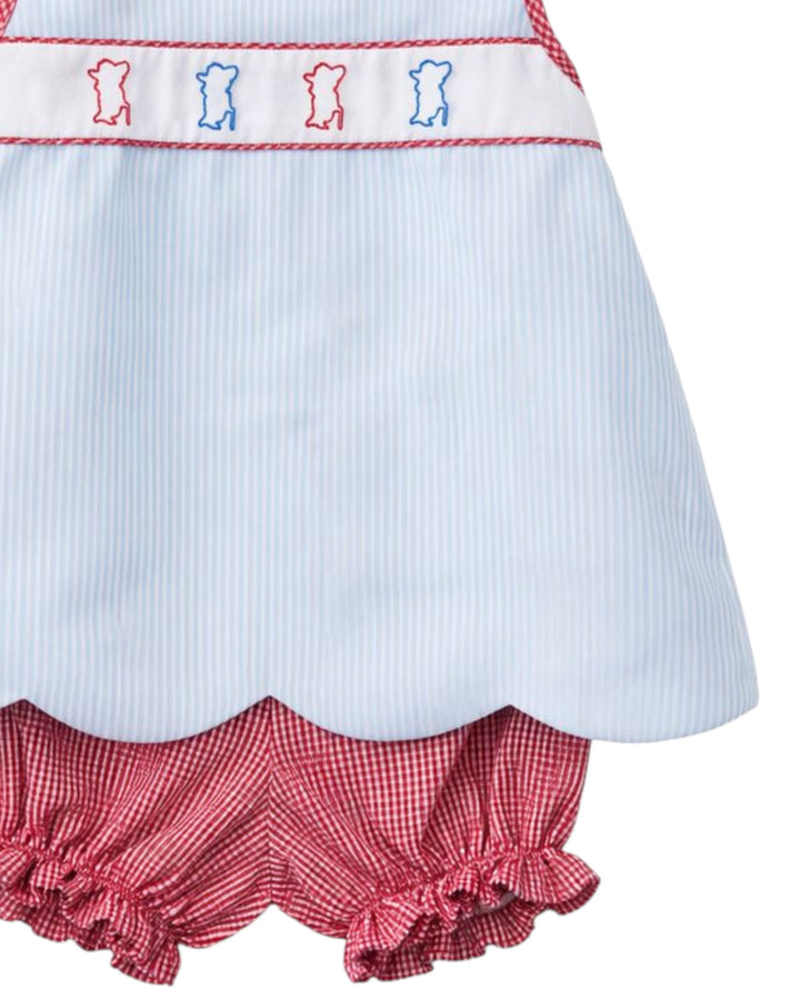 Close-up of a children's dress with red and white checkered ruffles and embroidered details.