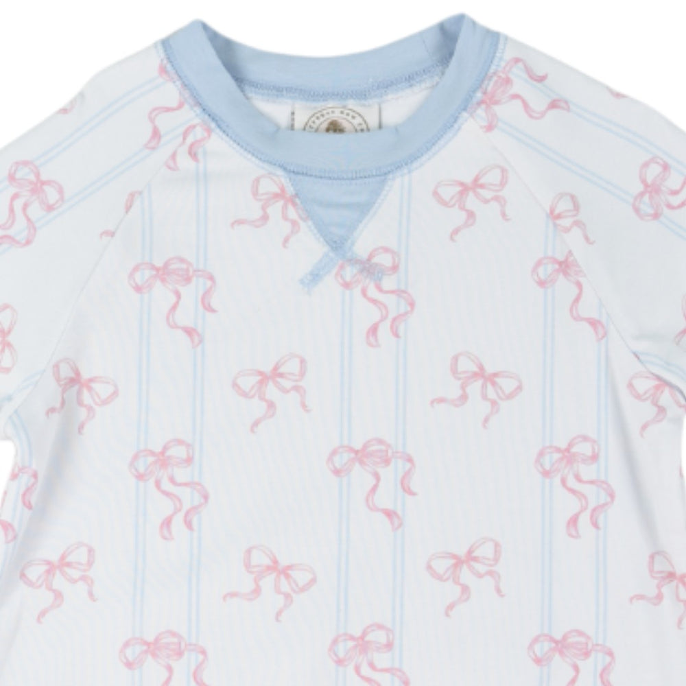 A close-up of a baby long-sleeve top featuring a white base with light blue vertical pinstripes, pink bow motifs, and a light blue crew neck, that store