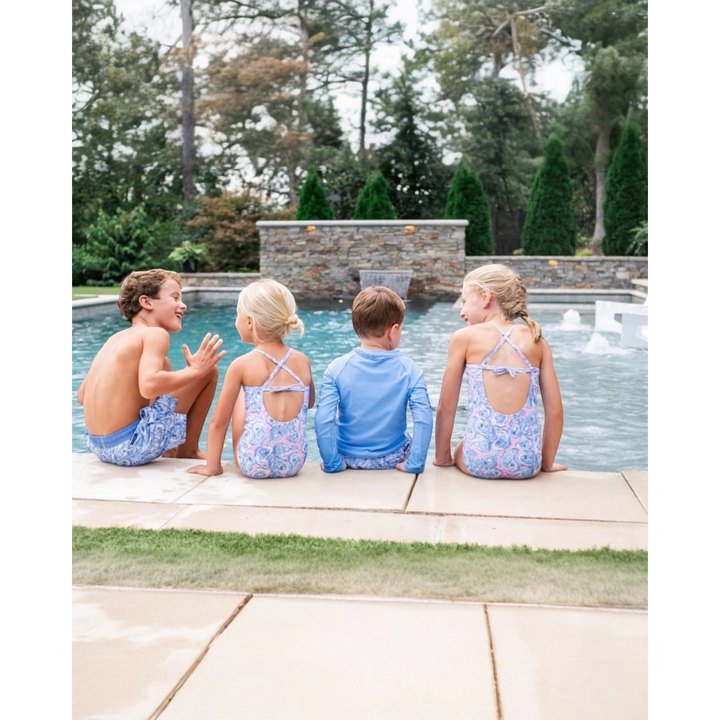 Four children sitting by a pool with trees in the background