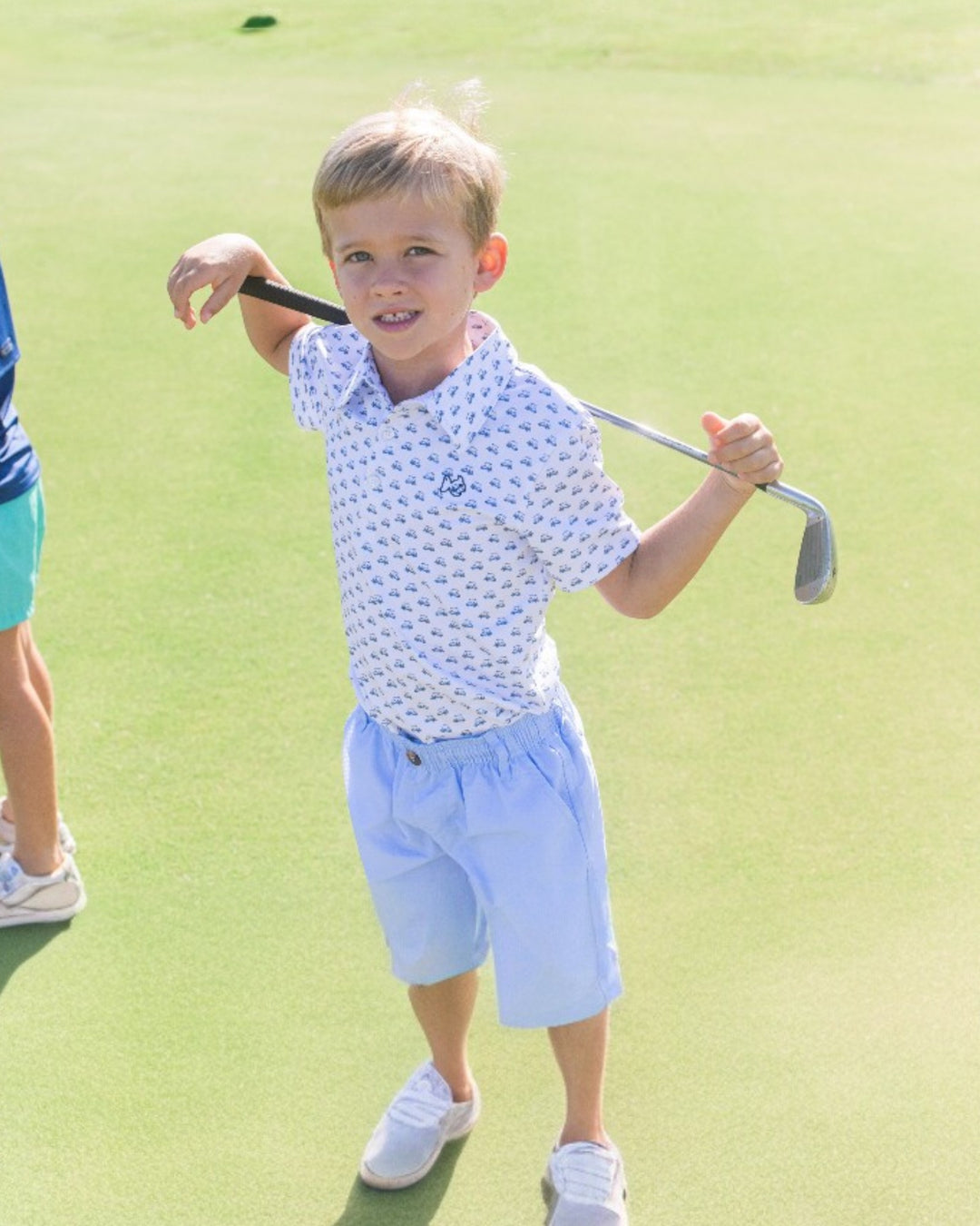 Child holding a golf club on a golf course