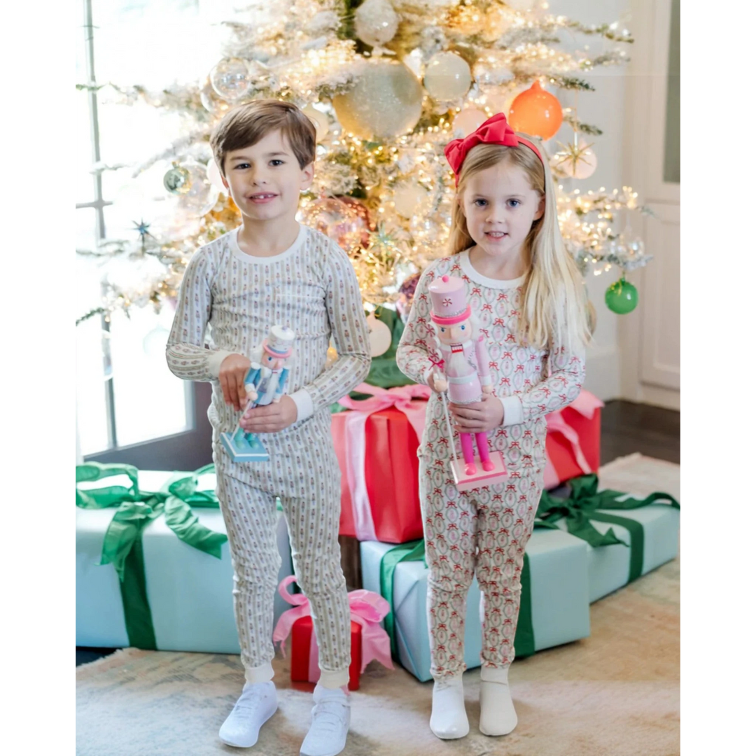 Two children in pajamas standing in front of a decorated Christmas tree with presents.