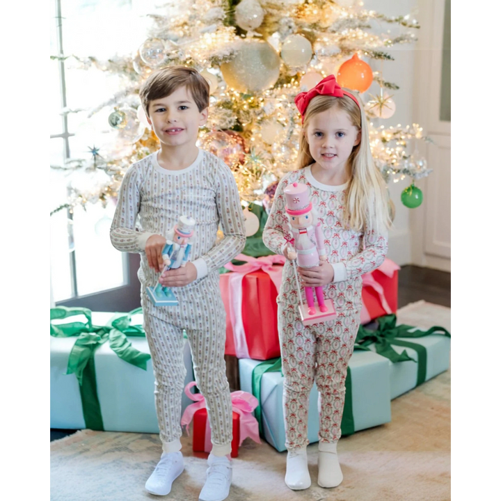 Two children in pajamas standing in front of a decorated Christmas tree with presents.