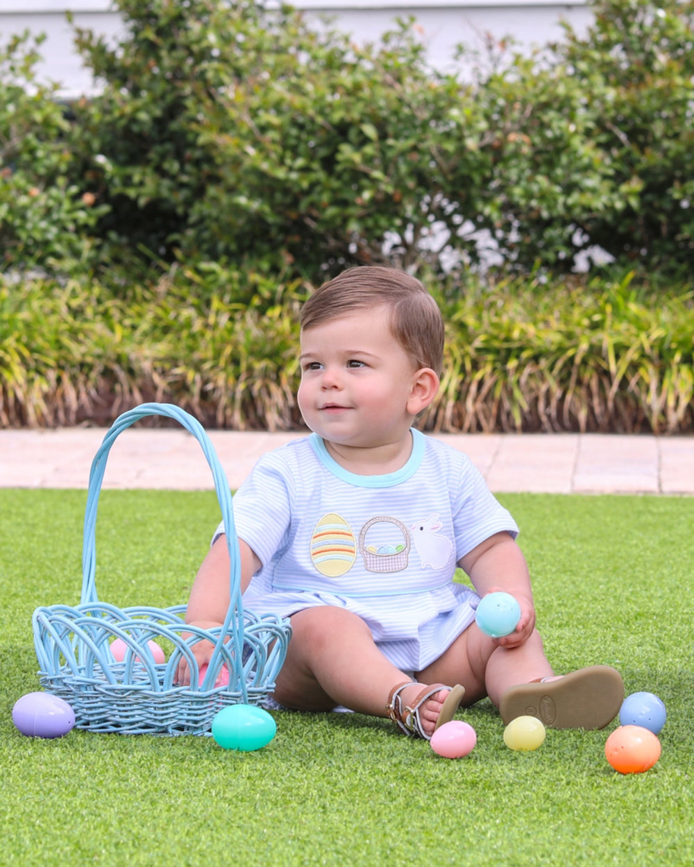 Child with Easter basket and eggs on grass