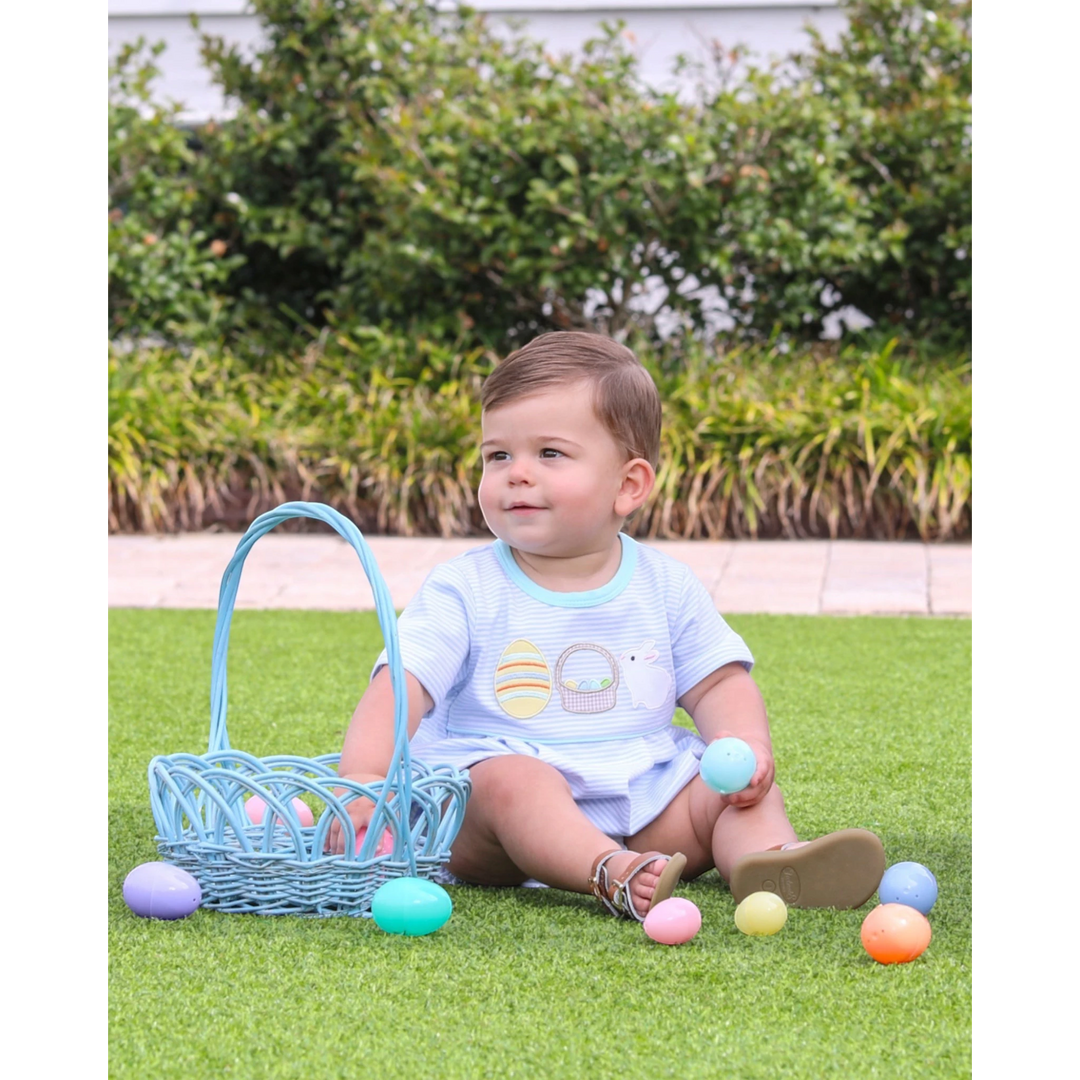Child with Easter basket and eggs on grass