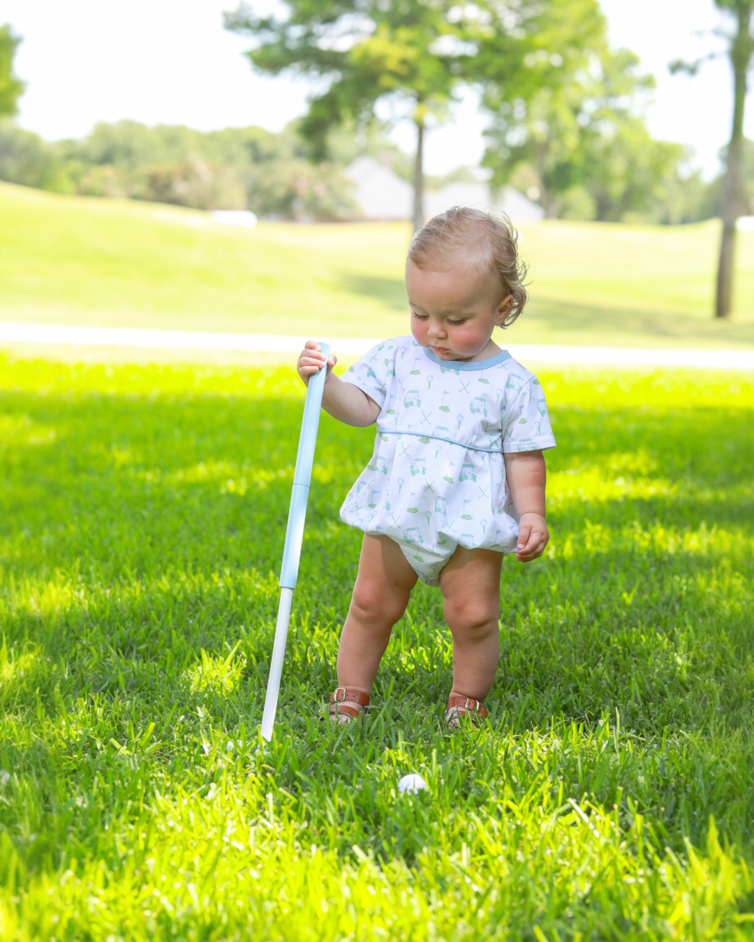 Baby in a park holding a white cane