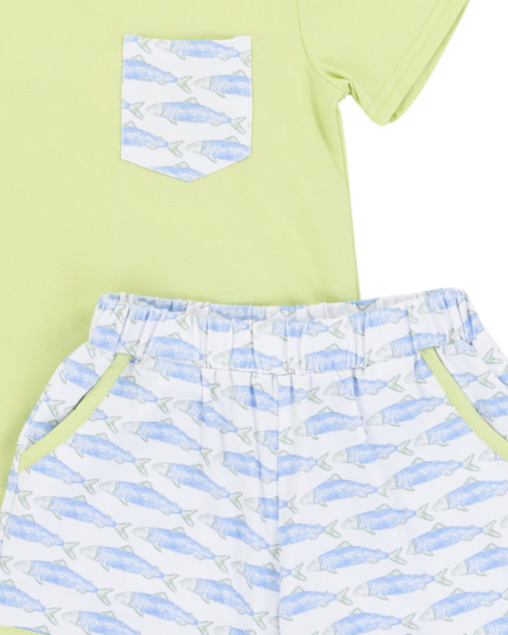 Light green t-shirt with a patterned pocket and white shorts with blue geometric pattern on a light green background