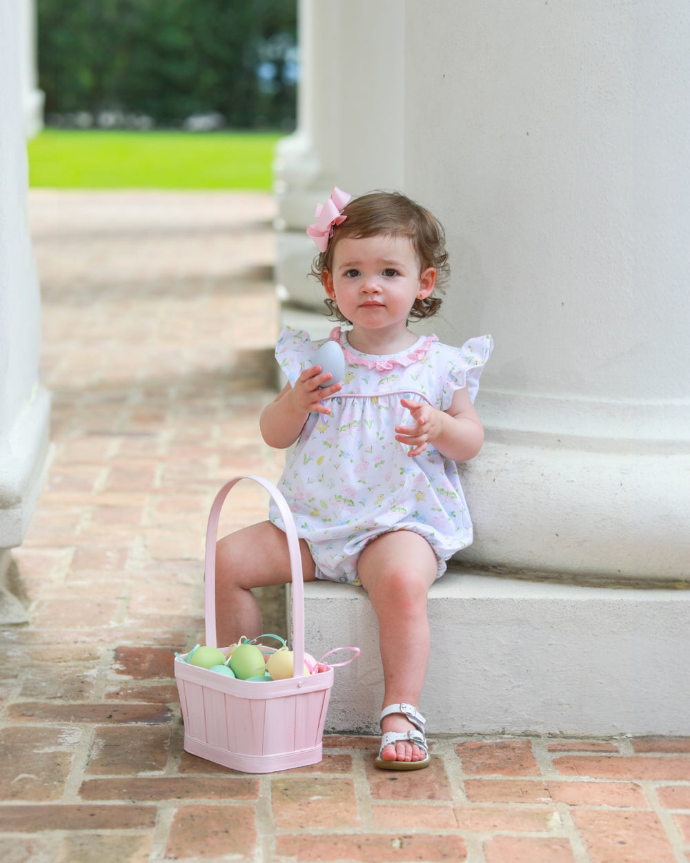 Child with Easter basket and eggs sitting on steps outdoors