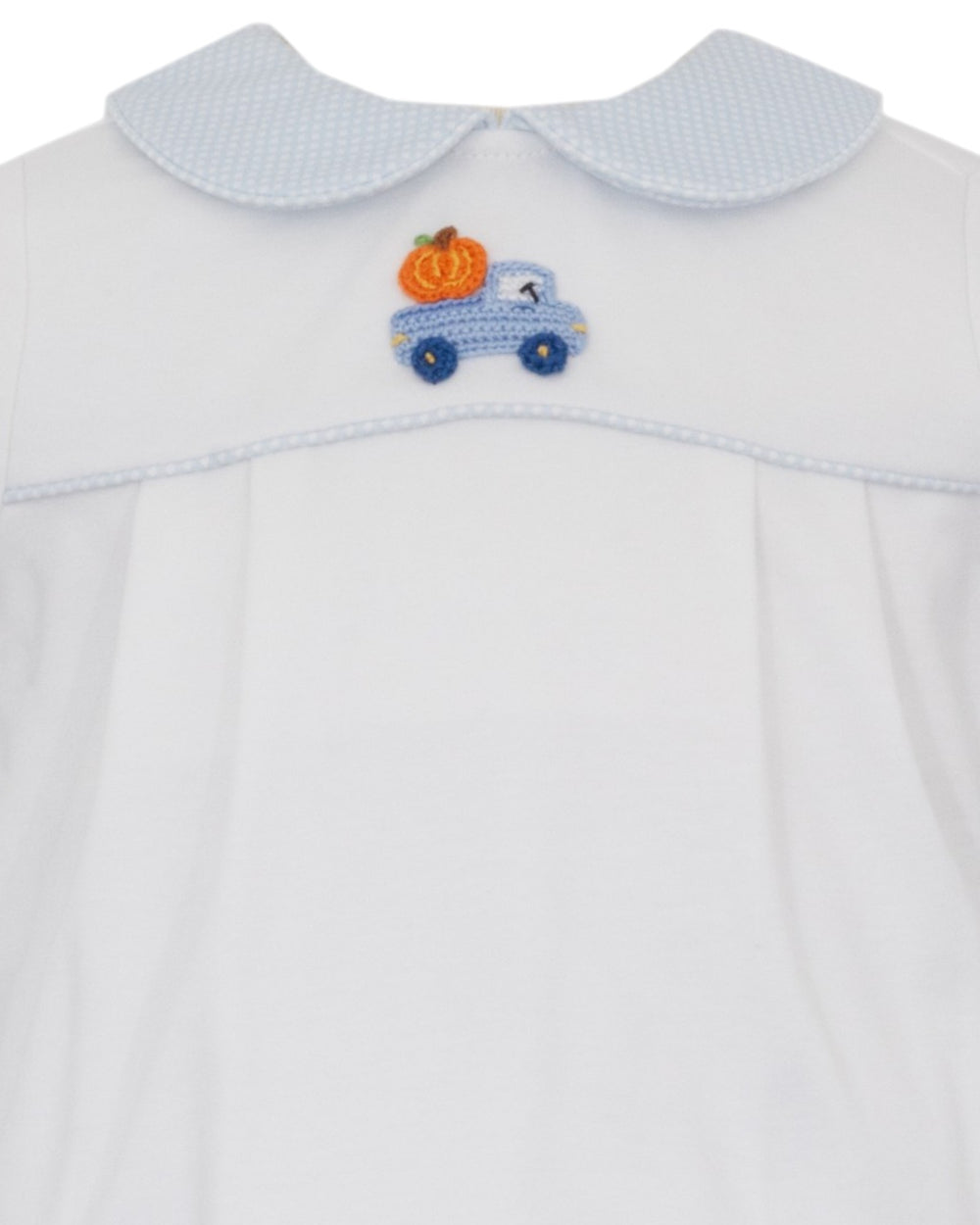 Close-up of a white baby dress with a light blue textured Peter Pan collar and a small embroidered blue truck with an orange pumpkin on the chest, that store
