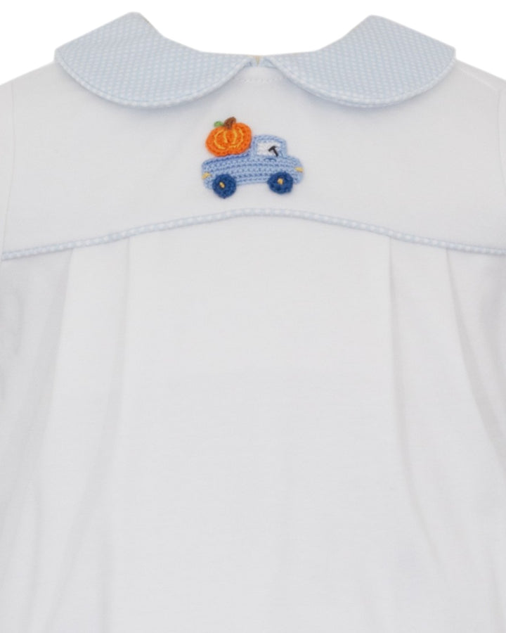Close-up of a white baby dress with a light blue textured Peter Pan collar and a small embroidered blue truck with an orange pumpkin on the chest, that store