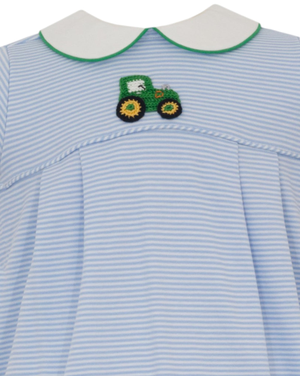 A close-up of a children's dress with light blue and white horizontal stripes, featuring a white Peter Pan collar with green trim and a green embroidered tractor patch on the chest, that store