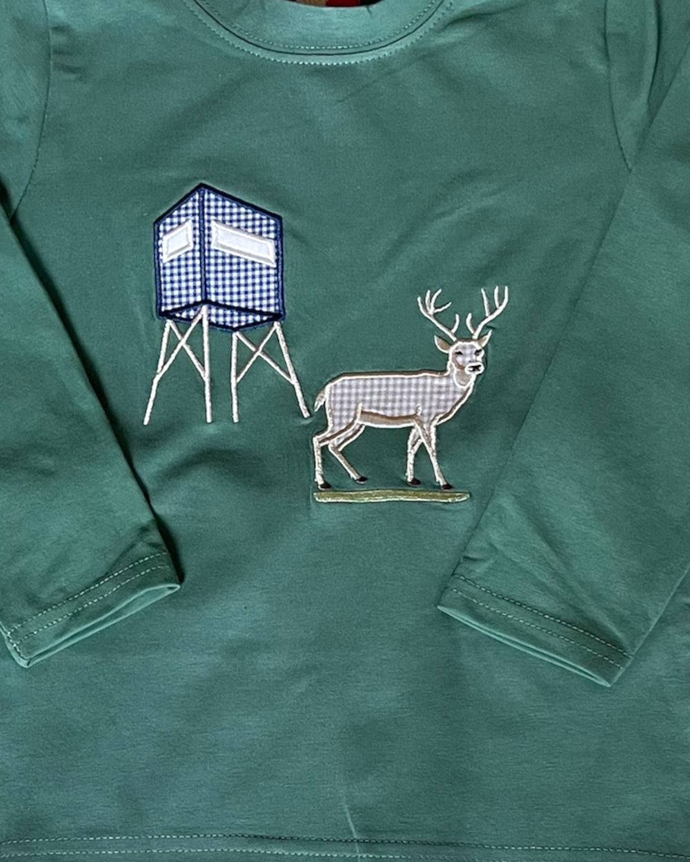 Green long-sleeve shirt with a deer and hunting blind design on a green background