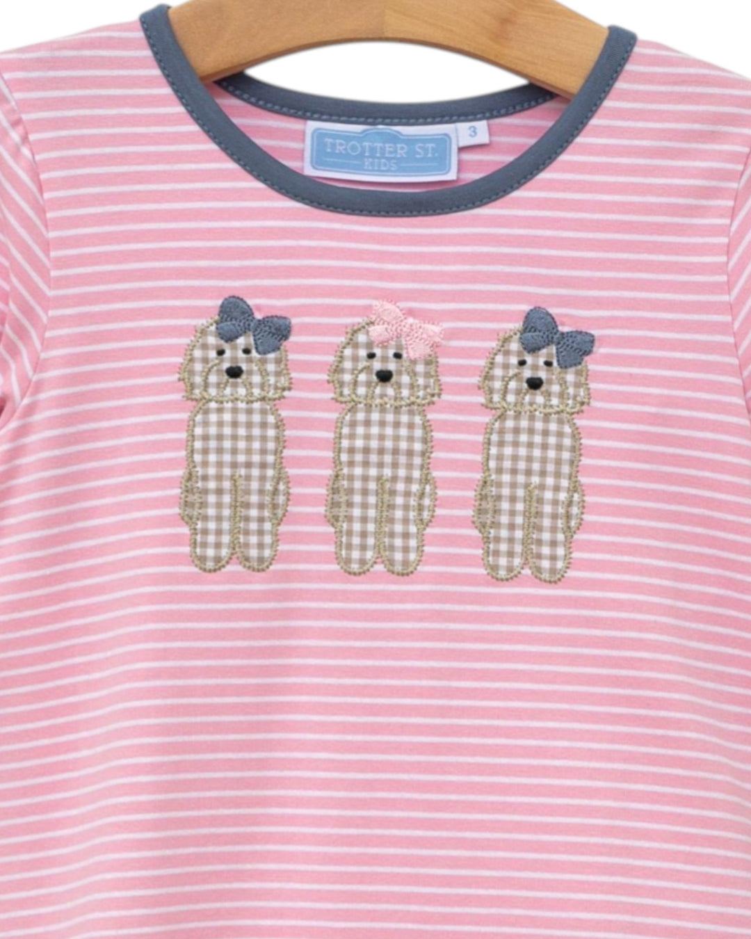 Pink and white striped shirt with dog appliqués on a hanger