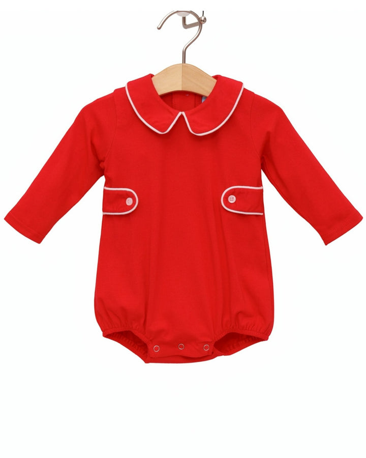 A bright red baby romper with a white-trimmed Peter Pan collar and matching white piping details on the chest pockets, hanging on a wooden hanger against a plain white background, that store