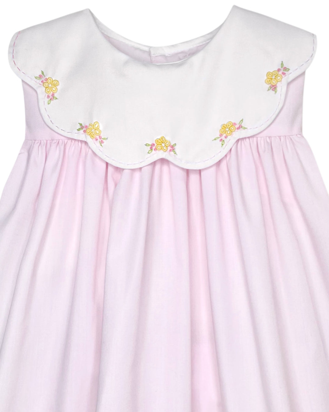 Pink dress with white embroidered collar and yellow flowers on a plain background