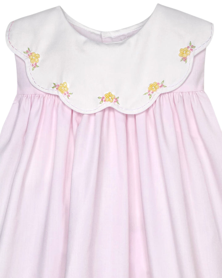 Pink dress with white embroidered collar and yellow flowers on a plain background
