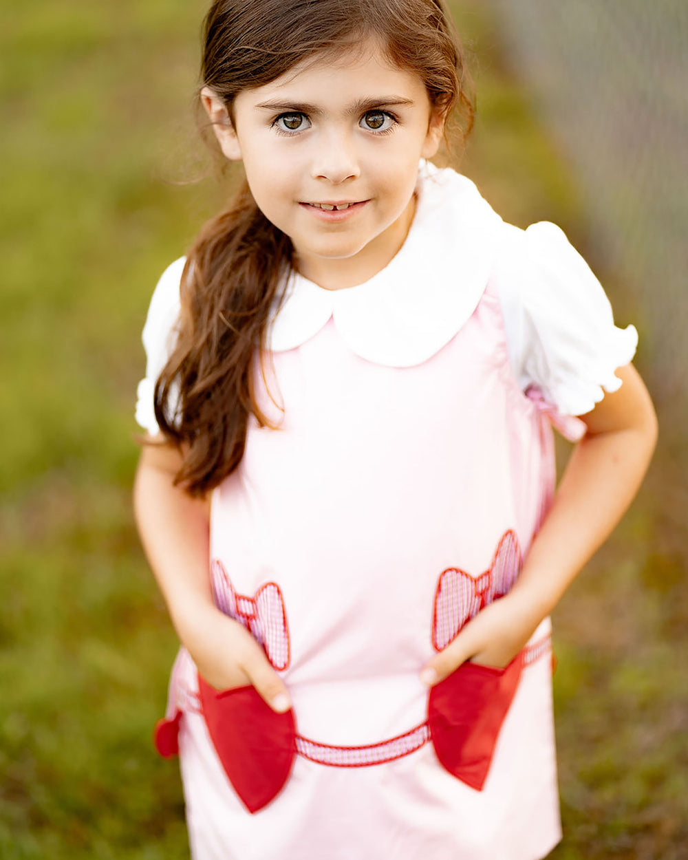 Young girl wearing a white dress with red accents outdoors