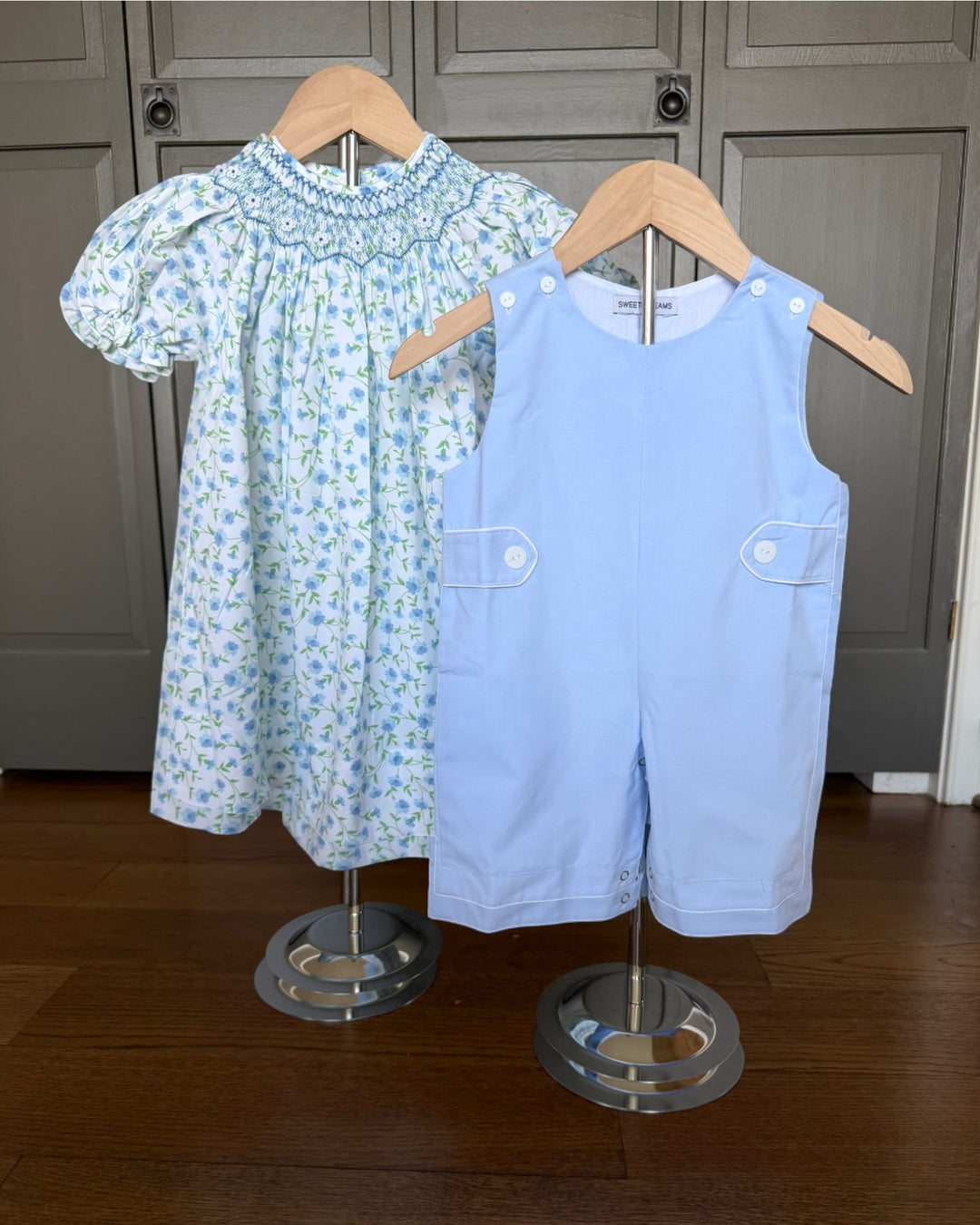 Children's dress and overalls on mannequins against a wooden floor background