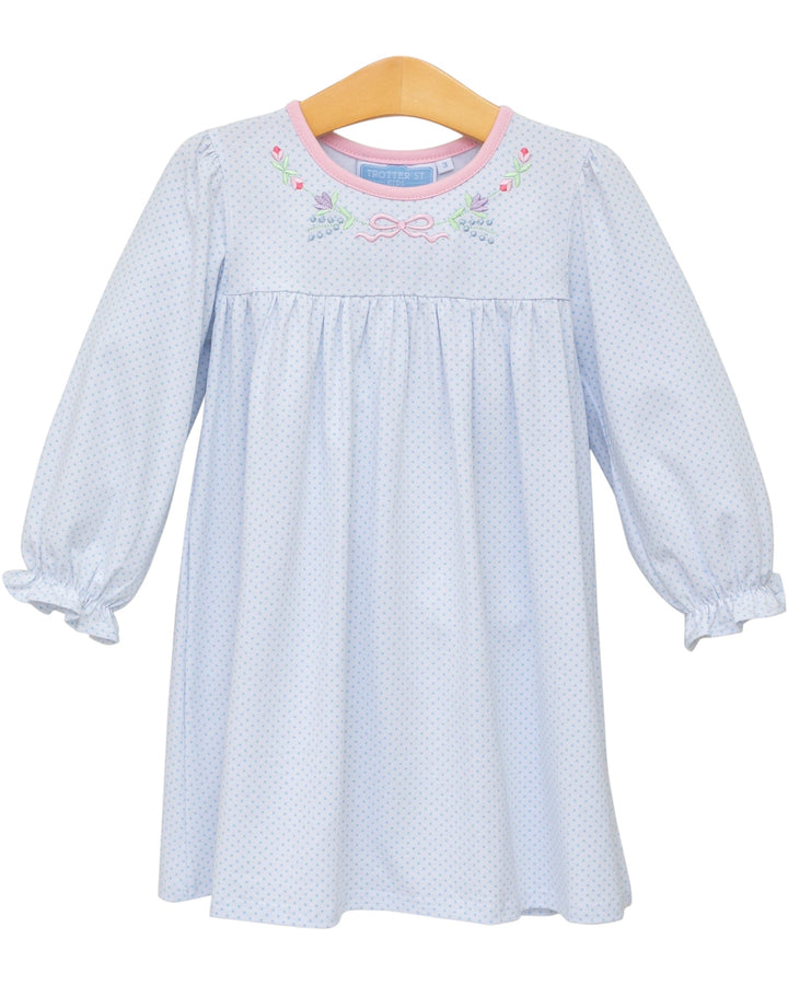 Light blue dress with floral embroidery on a wooden hanger against a white background