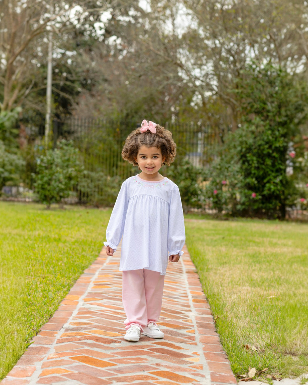 Young girl standing on a brick path in a park