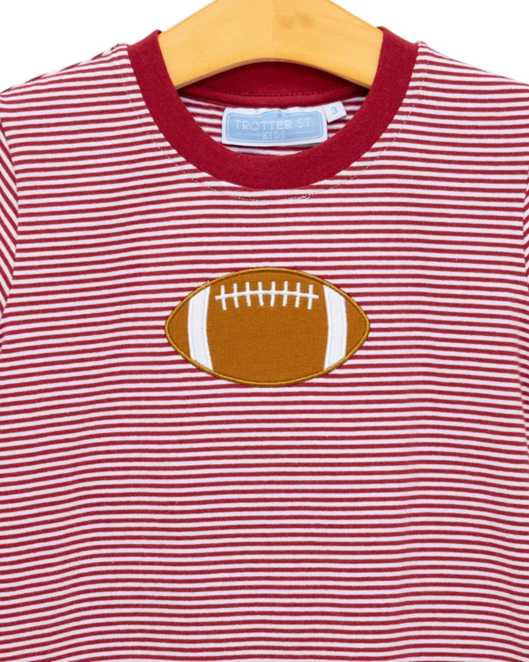 Red and white striped shirt with a football design on a hanger