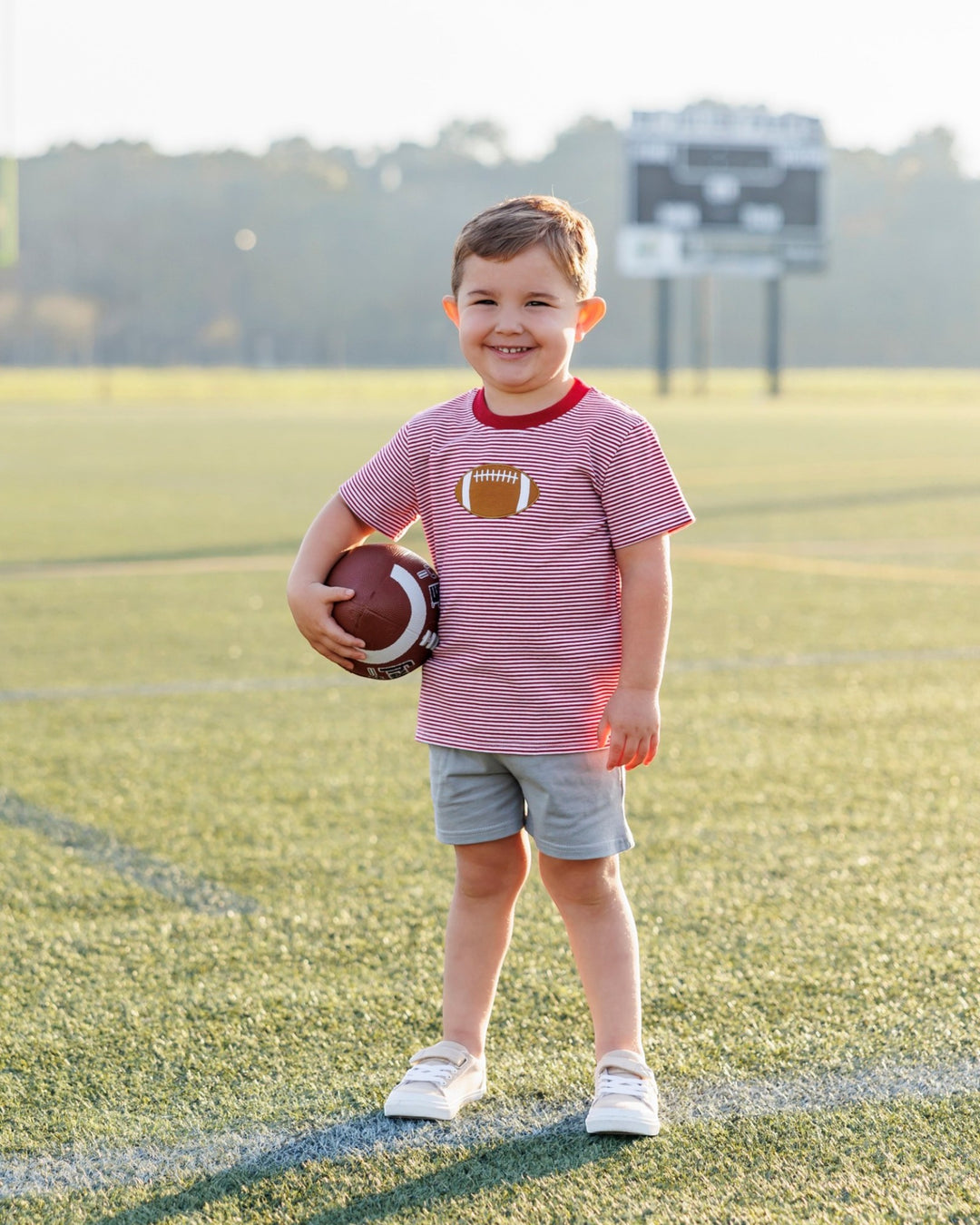 Child holding a football on a sports field