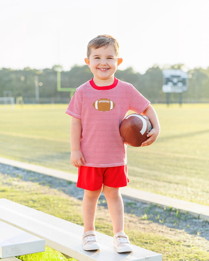Child holding a football on a sports field