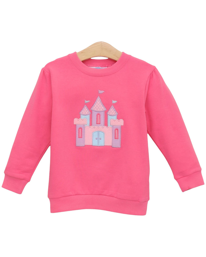 A pink long-sleeve crewneck sweatshirt for kids, featuring a light blue and lavender castle graphic on the front, displayed on a wooden hanger against a white background, that store