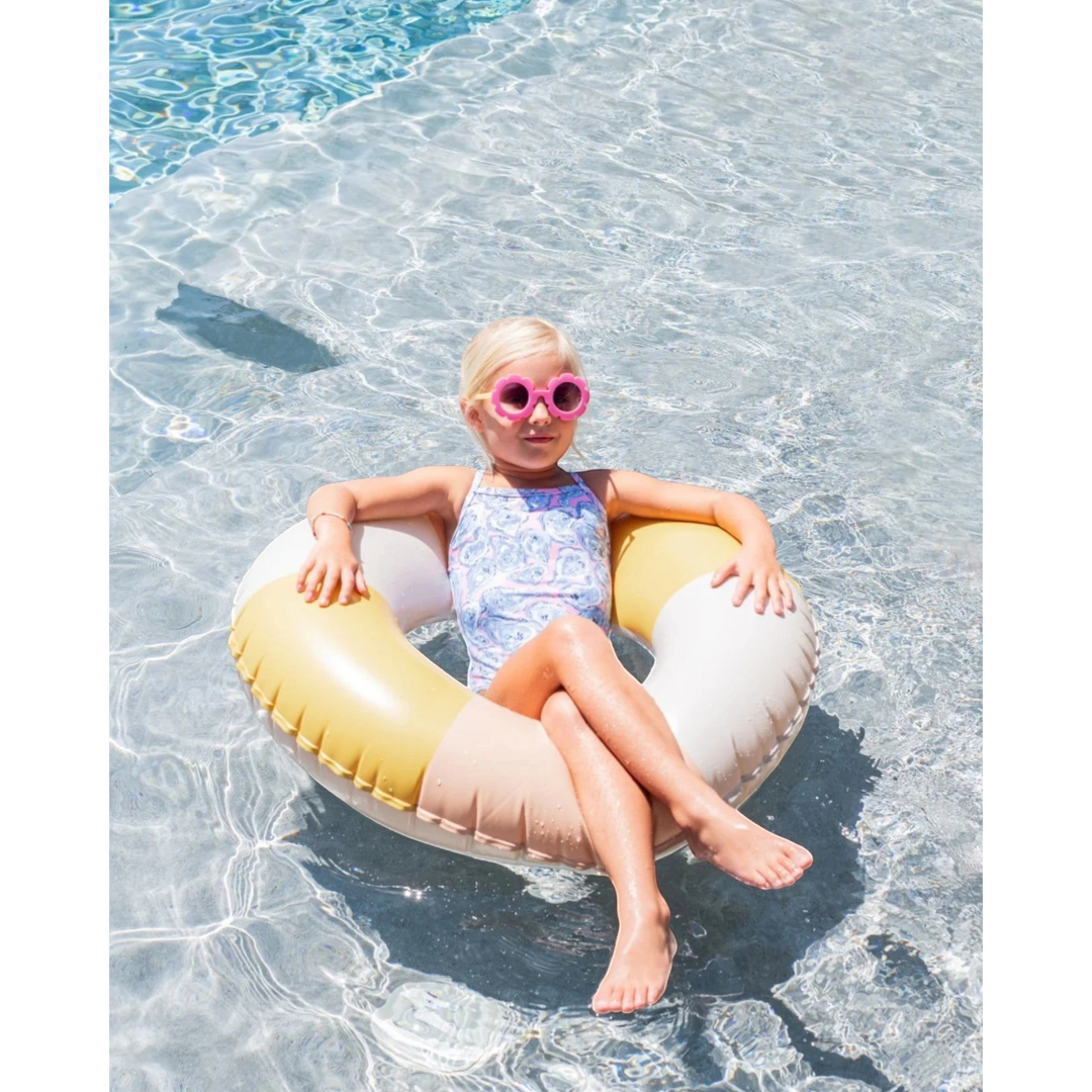 Child in a pool with a colorful inflatable ring and sunglasses