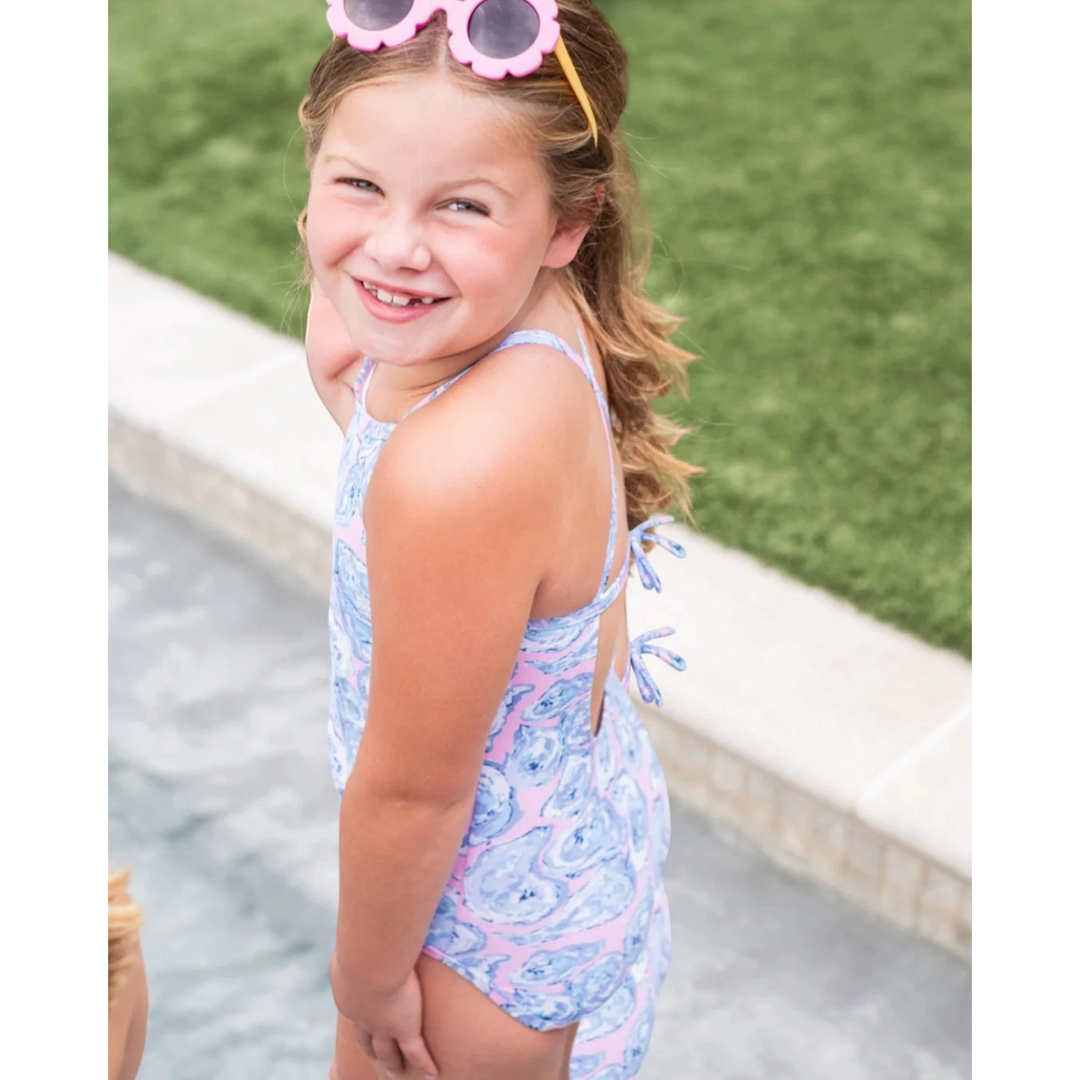 Young girl in a colorful swimsuit standing by a poolside.