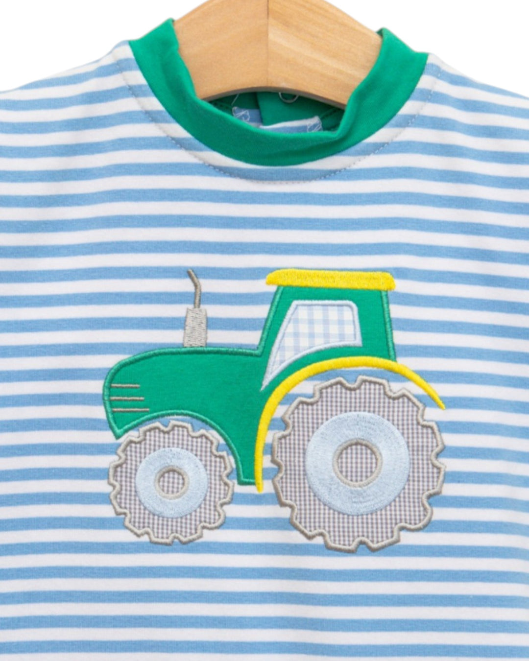 Children's shirt with a green tractor applique on a blue and white striped background.