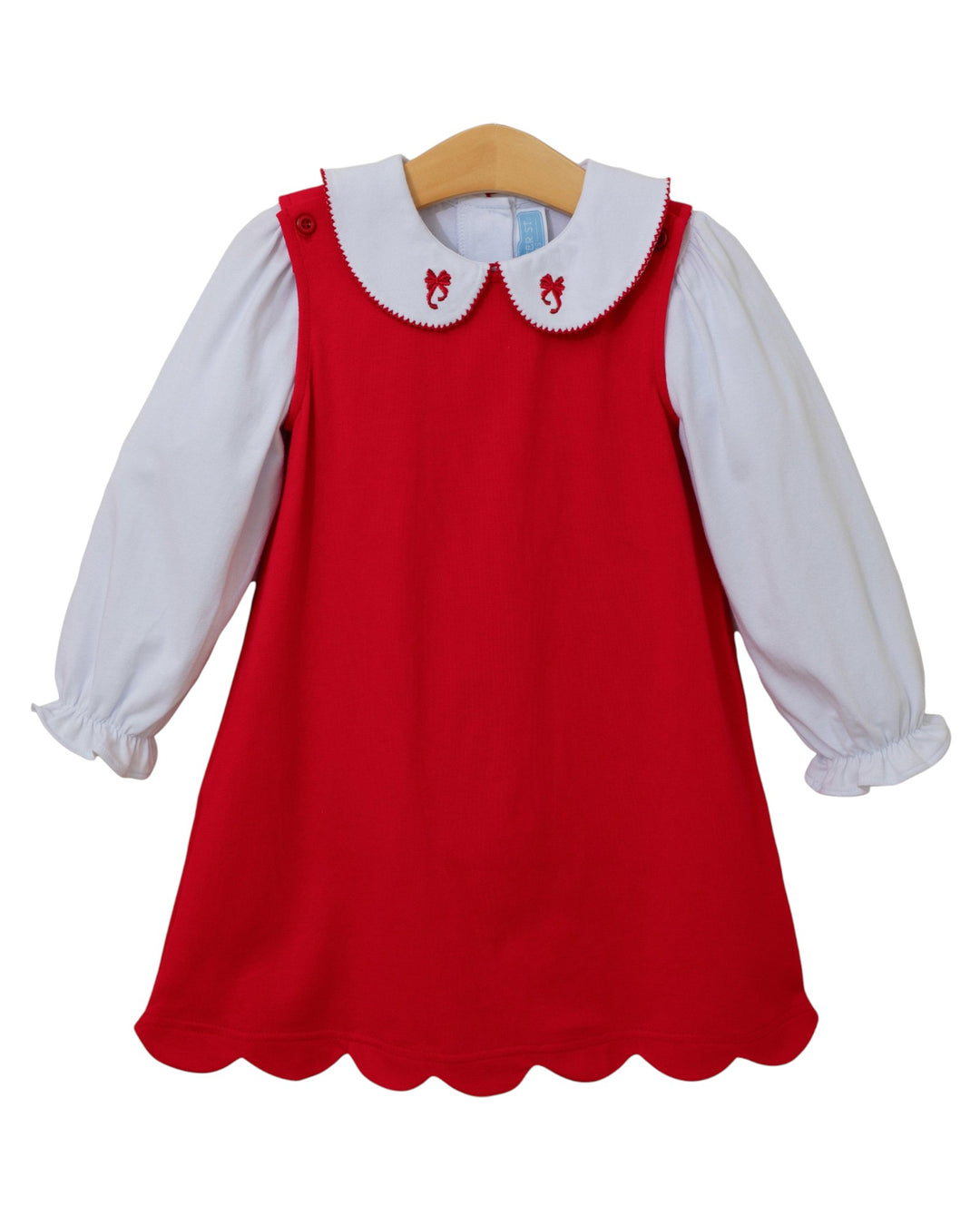 Red dress with white collar and long-sleeve shirt on a wooden hanger against a white background