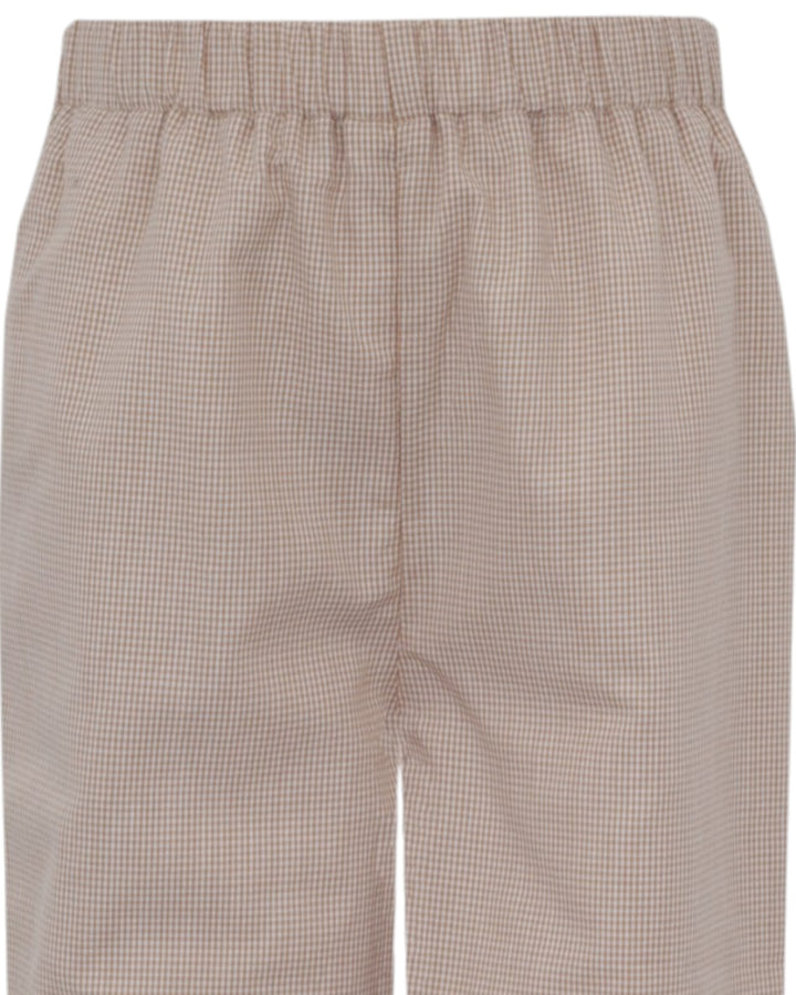Close-up of a pair of shorts with an elastic waistband, featuring a fine beige and white gingham check pattern, that store