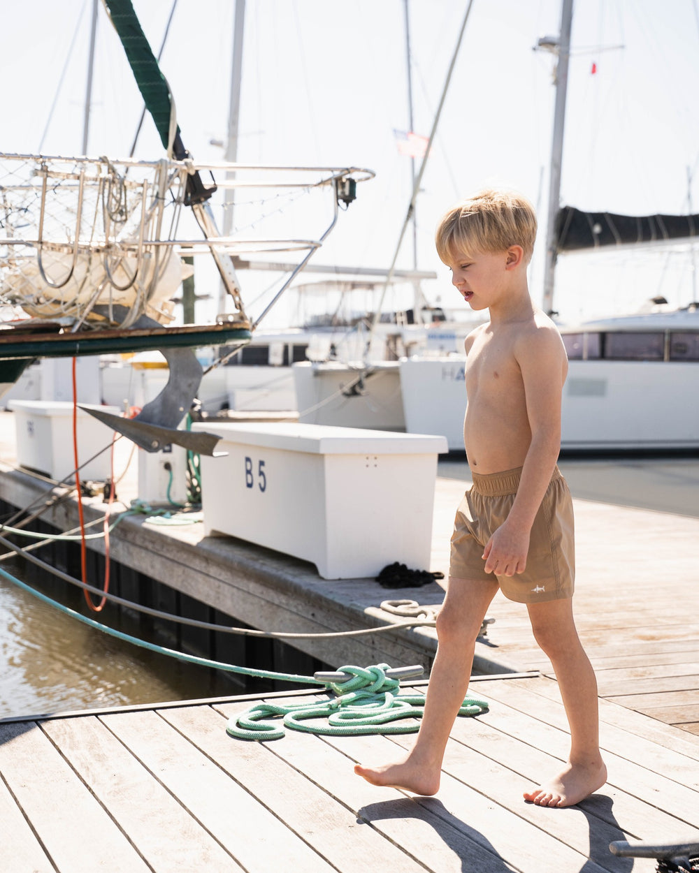 Young boy standing on a dock by a sailboat