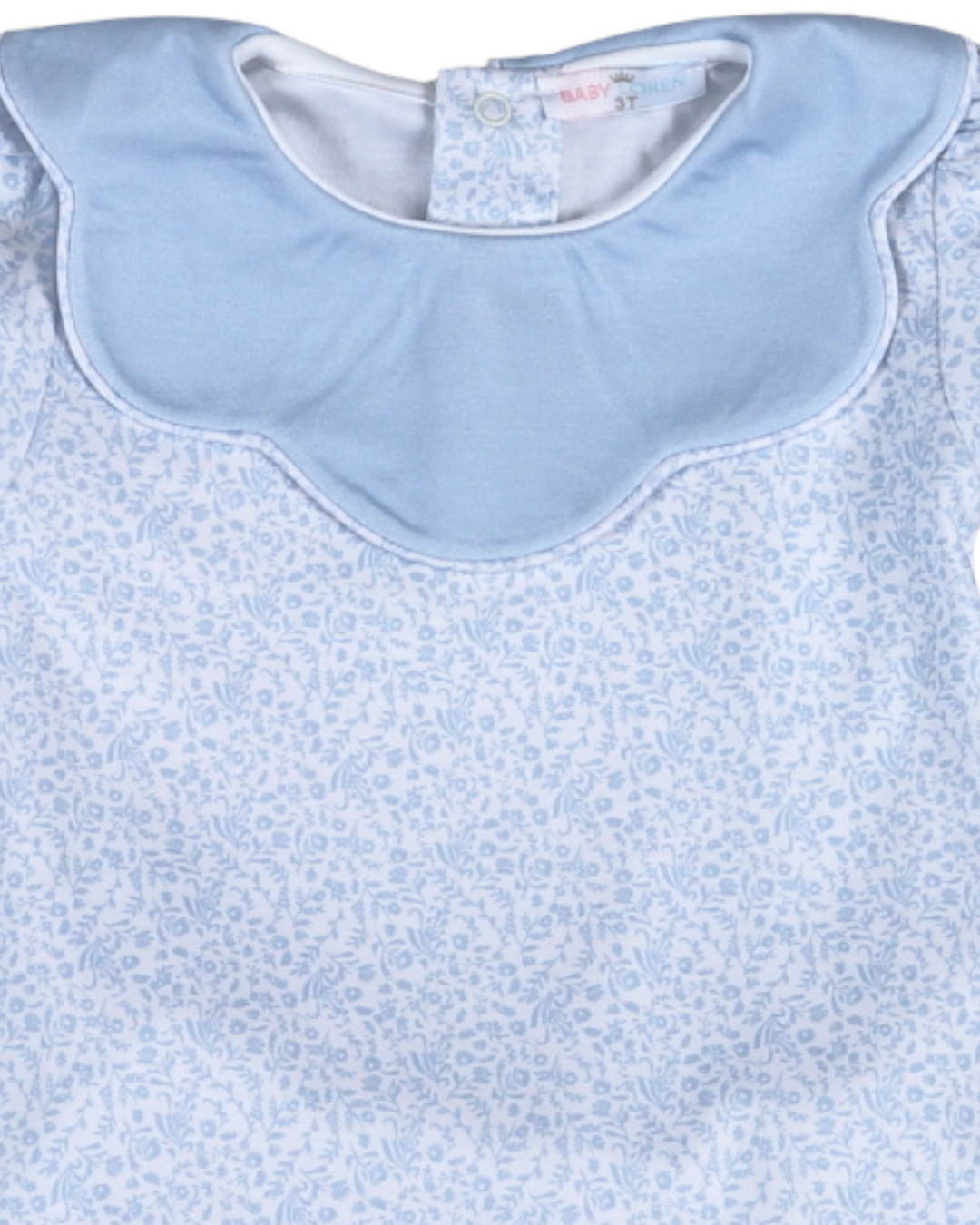 Baby bib with blue collar on a light blue floral patterned fabric