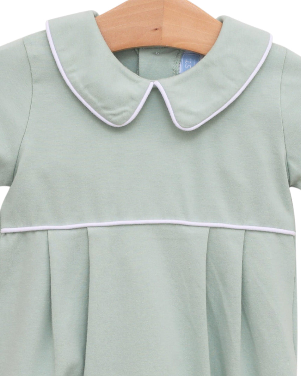 Light green dress with white trim on a wooden hanger against a white background